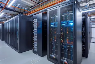 Rows of active server racks with multicolored status lights inside a modern federal data center facility.